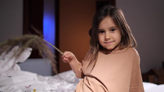portrait of a little girl with a twig in her hand. Little girl wants to tickle.