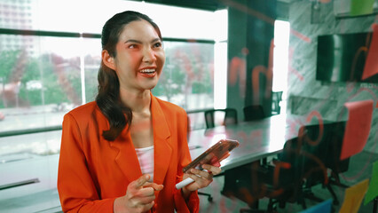 Portrait of young professional businesswoman take a photo with sticky notes. Project manager using...