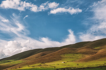 Vast rolling hills under a vivid blue sky with wispy clouds, creating a tranquil scene