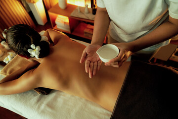 Masseur hands pouring aroma oil on woman back. Masseuse prepare oil massage procedure for customer...