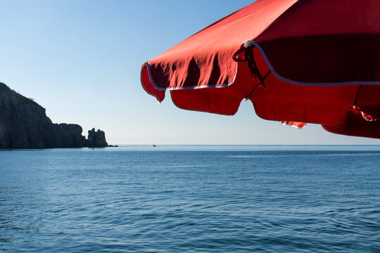red parasol on the jetty and cliff silhouette at the seaside