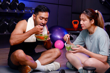 Young men and women exercising and eating a healthy mixed vegetable salad.