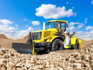Obraz premium Bulldozer and stone quarry worker. Development mineral deposits. Bulldozer at construction site of highway. Man worker takes notes while standing on territory stone quarry. Bulldozer under blue sky