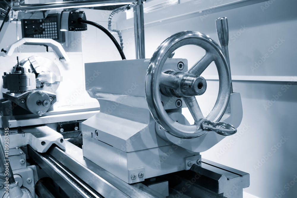 Poster A lathe machine with a white handle and a silver wheel. The handle is attached to a machine that is used to cut metal