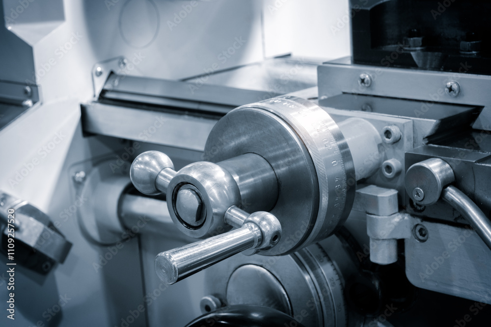 Poster A lathe machine with a white handle and a silver wheel. The handle is attached to a machine that is used to cut metal