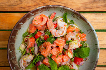 Top view of spicy salmon and shrimp salad in bowl place on wooden planks