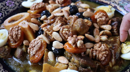 Traditional Moroccan Meat with Prunes, Nuts, and Boiled Eggs in Ornate Peacock Platter – Authentic North African Cuisine for Festive Occasions  
