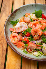 Spicy salmon and shrimp salad in bowl place on wooden planks