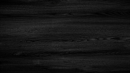 A black wooden surface with a grain pattern. The surface is dark and has a natural texture. The wood appears to be aged and has a rich, deep color