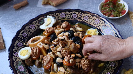 Traditional Moroccan Meat with Prunes, Nuts, and Boiled Eggs in Ornate Peacock Platter – Authentic North African Cuisine for Festive Occasions  
