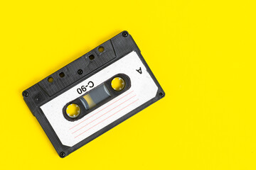 Old vintage audio cassette on yellow background.