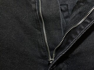 Metal split zipper on the waistband of jeans. Denim background. Backgrounds and fabrics.