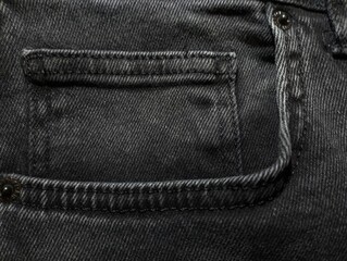 Background of dark gray jeans with a seam width and a small pocket. The theme of clothing fabrics and fashion.
