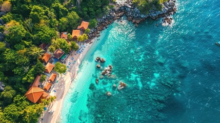 Obraz premium Aerial view of tropical beach, resort, ocean, and lush green foliage.
