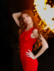 Fire and Grace: A young beauty in a red dress posing against a backdrop of flames