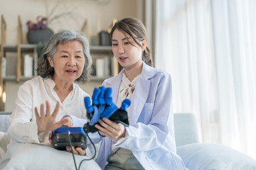 asian senior woman learning to practice a hand function rehabilitation training device with physiotherapist,a young female health care worker advice elderly hands exercise