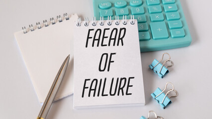 Hand with red pen, Calculator and white background. Fear of Failure sign in the notepad