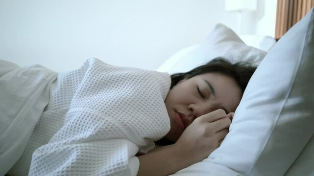 A serene scene of a young woman peacefully sleeping in a cozy bedroom. The soft lighting and comfortable bedding enhance the sense of tranquility and restfulness. This image captures the beauty of rel