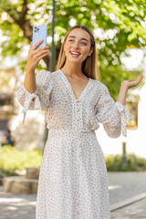 Young pretty woman blogger taking selfie on smartphone, communicating video call online with...