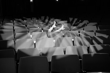 Naklejka premium sie streckt ihre beine über die leeren Ränge im Theater