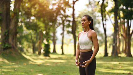 A woman stands tall in Tadasana, aligning her posture with hands relaxed, eyes focused, and surrounded by nature's calming greenery