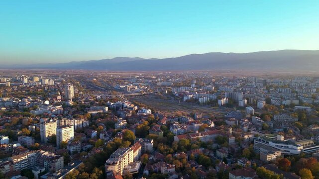 Aerial drone footage of a sunset over the city of Plovdiv in Bulgaria. Ancient city of Filipopolis filmed from above on a warm autumn afternoon. European city seen from a helicopter establishing shot.