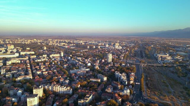 Aerial drone footage of a sunset over the city of Plovdiv in Bulgaria. Ancient city of Filipopolis filmed from above on a warm autumn afternoon. European city seen from a helicopter establishing shot.