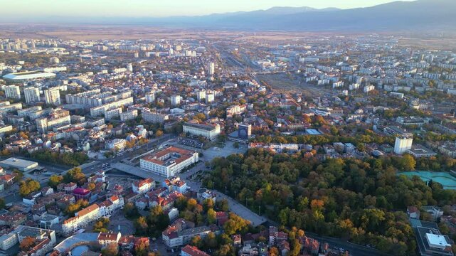 Aerial drone footage of a sunset over the city of Plovdiv in Bulgaria. Ancient city of Filipopolis filmed from above on a warm autumn afternoon. European city seen from a helicopter establishing shot.