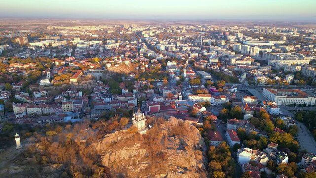 Aerial drone footage of a sunset over the city of Plovdiv in Bulgaria. Ancient city of Filipopolis filmed from above on a warm autumn afternoon. European city seen from a helicopter establishing shot.