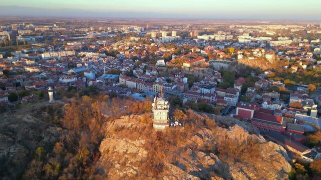 Aerial drone footage of a sunset over the city of Plovdiv in Bulgaria. Ancient city of Filipopolis filmed from above on a warm autumn afternoon. European city seen from a helicopter establishing shot.