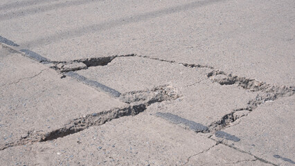 Cracks and broken texture with collapse of the old badly damaged concrete street surface
