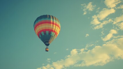 Fototapeta premium Colorful hot air balloon floats in a clear blue sky with fluffy clouds.