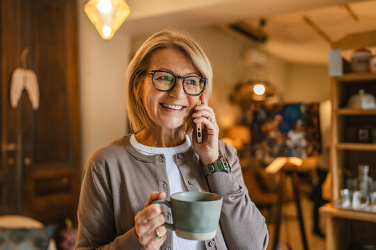 mature woman entrepreneur have a phone call and drink coffee on work