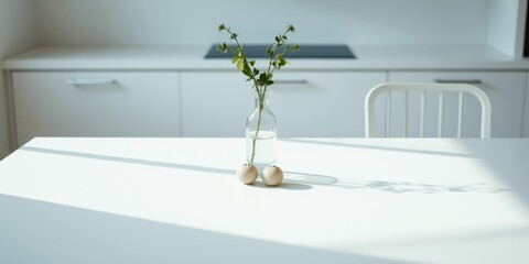 Simple Minimalist Kitchen Table Setting with a Glass Vase of Green Greenery and Two Round Objects