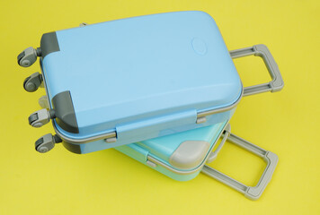 Two blue travel suitcases on yellow background.