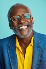 Fototapeta premium A man with a beard and glasses is smiling and wearing a blue jacket and yellow shirt. He looks happy and content