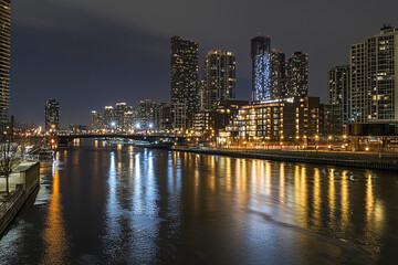 Obraz premium Nighttime cityscape view over the river with illuminated buildings