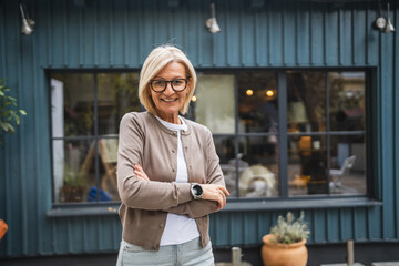 Portrait of woman entrepreneur stand arm crossed in front restaurant