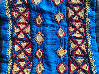 Kutchi Bharat embroidery showcasing intricate triangular patterns, highlighted by a beige thread border on luxurious blue raw silk