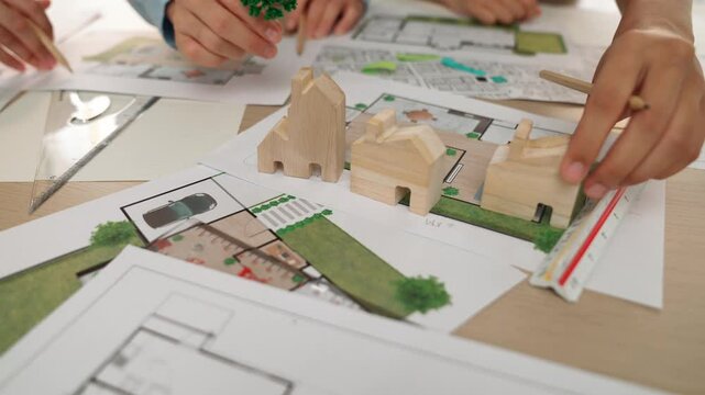 Architects determine position of tree or house using building blueprint on messy table with architectural project and measurement tool scattered around. Business and environment concept. Delineation.