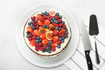 Delicious chocolate sponge cake with berries, server and knife on light table, top view