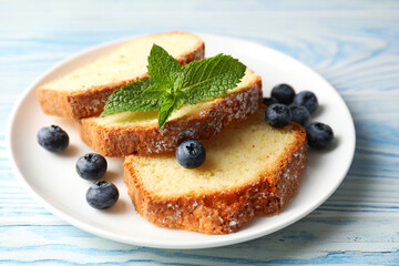 Freshly baked sponge cake, blueberries and mint on light blue wooden table, closeup