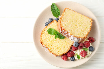 Freshly baked sponge cake, whipped cream, berries and mint on white wooden table, top view. Space for text