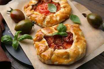 Tasty galettes with tomato and basil on wooden table, closeup