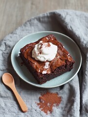 Delightful dessert flat lay featuring a small plate with brownie and whipped cream on soft linen background for home food