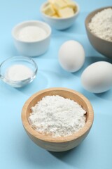 Baking powder and other ingredients for making dough on light blue background, closeup