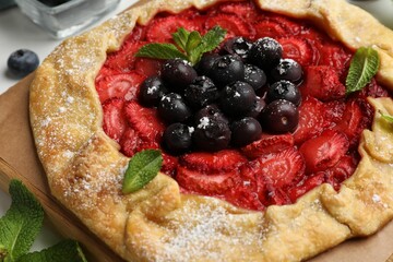Tasty galette with berries and mint on table, closeup