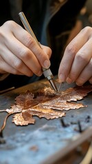 Obraz premium Close-up of an artisan's hands crafting a detailed copper leaf using specialized engraving tools on a workbench.