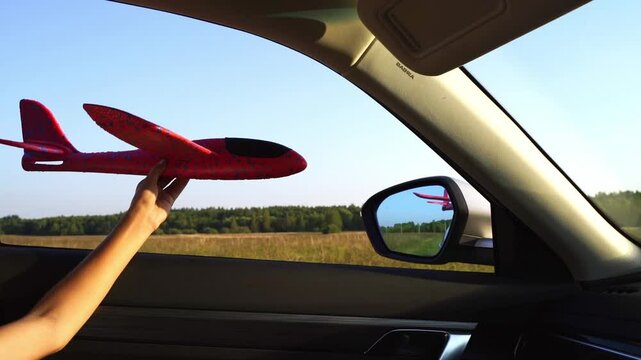 boy launches glider plane in car window