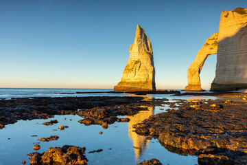 Le soleil se couche sur l'arche d'Étretat pendant la marée basse
